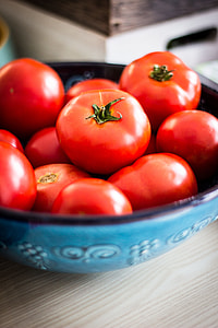 tomatoes in blue ceramic bowl on wooden table thumbnail