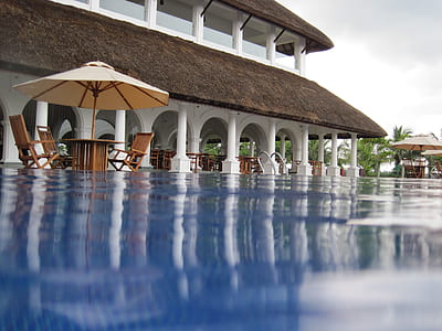 brown and white parasol umbrella near building and calm water thumbnail