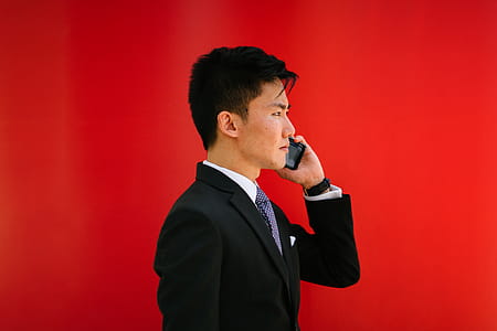Man Holding Smartphone Wearing Black Notched-lapel Suit Jacket thumbnail