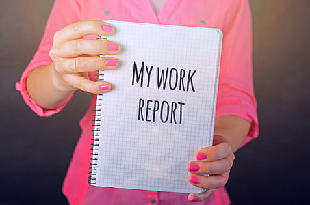 Woman in Pink Long-sleeved Shirt Holding White Book With My Work Report Text Print thumbnail