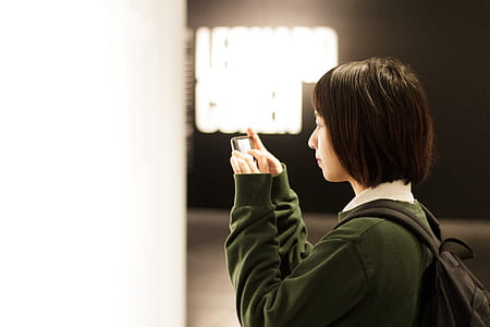 woman holding smartphone while taking photo thumbnail