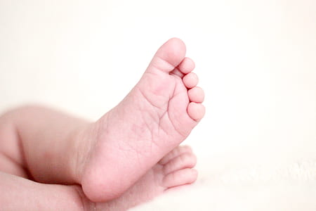 baby feet on white fabric sheet thumbnail