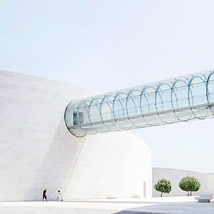 two people walking next to white concrete structure thumbnail