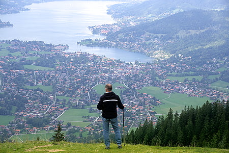 man holding gray stick standing on grass field facing village thumbnail