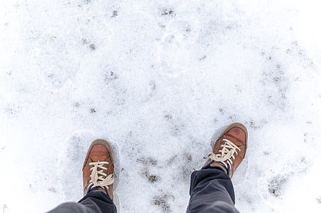 person on brown lace-up shoes standing on snow field thumbnail