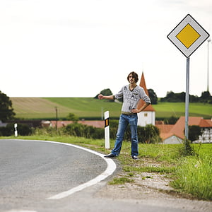 shallow focus photography of man standing beside road thumbnail