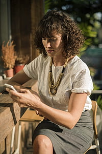 woman sitting on chair holding smartphone thumbnail
