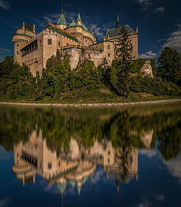 photo of brown and teal castle near body of water during daytime thumbnail