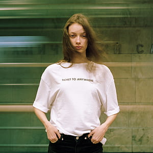woman in white and black crew-neck shirt standing near glass wall thumbnail