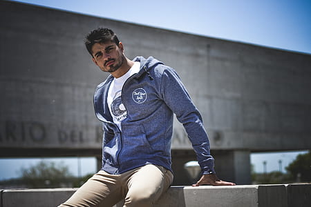 man sitting on wall wearing jacket thumbnail