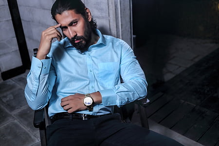man wearing blue dress shirt sitting on black armchair thumbnail