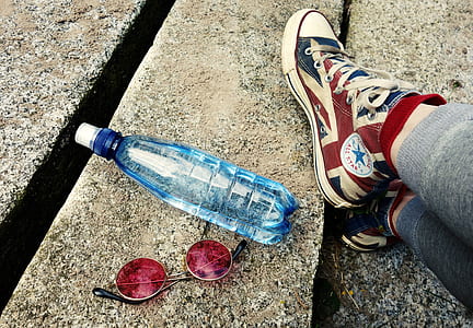 round brown framed red lens sunglasses beside blue plastic bottle on brown surface thumbnail