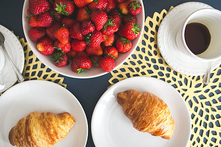 Fresh buttery croissants, hot cup of coffee and bowl with strawberries thumbnail