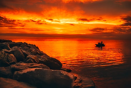 silhouette of boat on bodies of water at sunset thumbnail