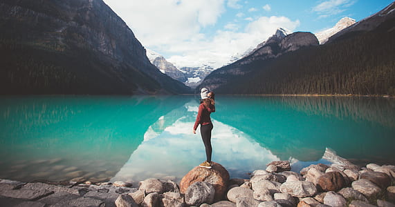 woman standing on stone looking on body of water thumbnail