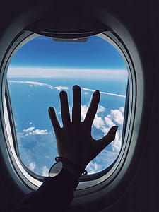 Photography of Person's Left Hand Touching an Airplane's Window thumbnail