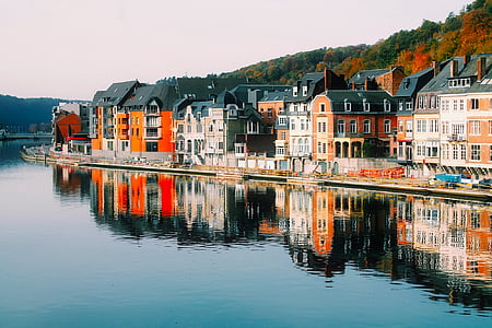 assorted-color concrete houses in front sea under cloudy sky thumbnail