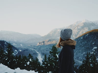 woman wearing grey knit cap standing on hill facing towards glacier mountain thumbnail