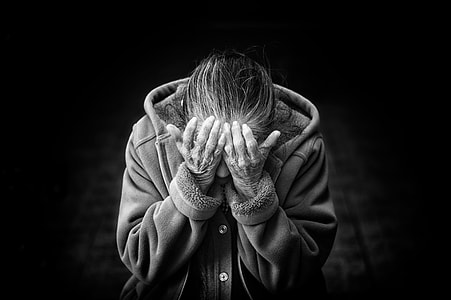 grayscale photo of person in button-up hooded jacket putting his hands in his eyes thumbnail
