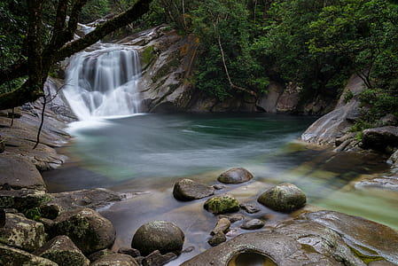 time-lapse photography of waterfalls surrounded with gray rocks and green trees during daytime thumbnail