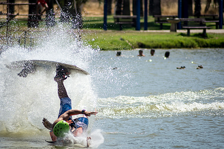 person hitting body of water upside down while his left foot on wakeboard thumbnail