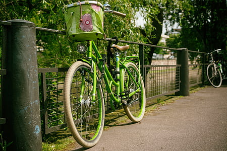 green commuter bike parked beside fence thumbnail