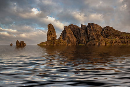 cliff and body of water under cloudy sky thumbnail