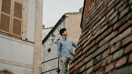 man wearing gray dress shirt standing near concrete houses thumbnail