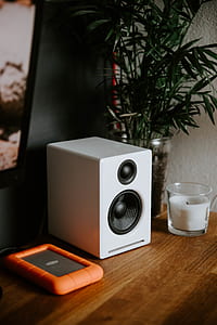 white portable speaker near candle on table thumbnail