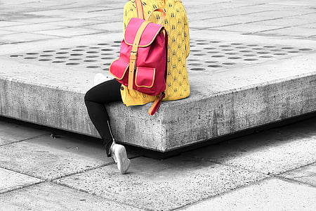 person sitting on gray surface wearing red backpack thumbnail