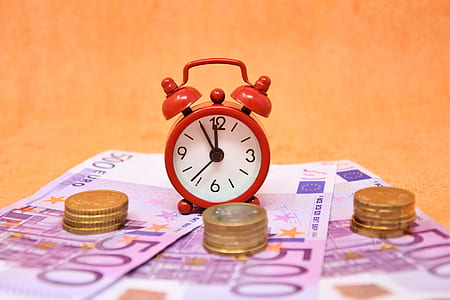 red and white analog desk clock on 500 Euro banknotes thumbnail