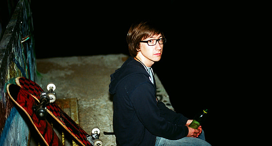 man sitting near two skateboards during night time thumbnail