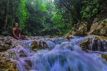 time lapse photo of man sitting beside flowing river during daytime thumbnail