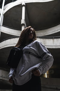 woman standing under white concrete building thumbnail