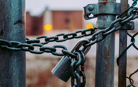selective focus photography of mesh fence tied with chains and padlock thumbnail