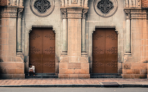 photo of person sitting beside cathedral door thumbnail