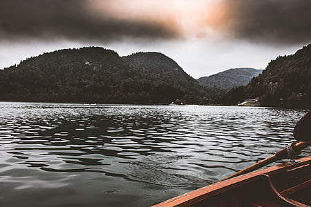 brown boat sailing surrounded by mountains thumbnail
