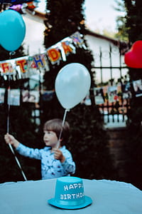 boy holding white and blue balloons thumbnail