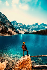 man standing on brown rock near body of water during daytime thumbnail