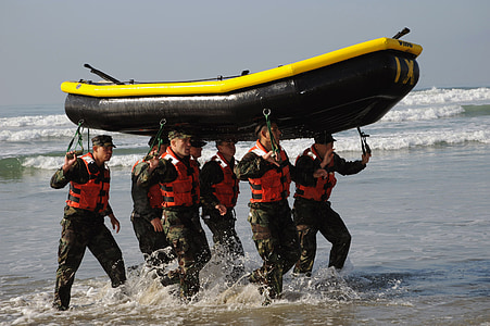 group of men carrying black and yellow inflatable boat thumbnail