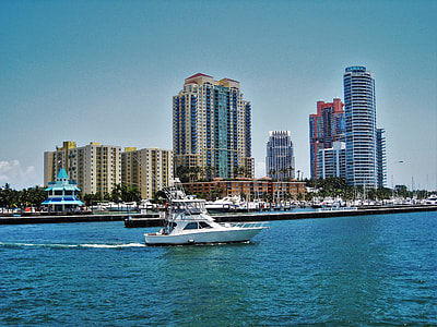 white motorboat in body of water near high-rise buildings thumbnail