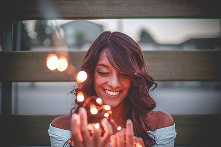 Selective Focus Photography Of Smiling Woman Holding String Lights thumbnail