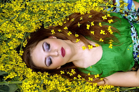 woman in green sleeveless top laying on yellow flowers thumbnail