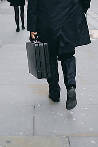 man in black coat and pinstriped pants walking carrying briefcase thumbnail