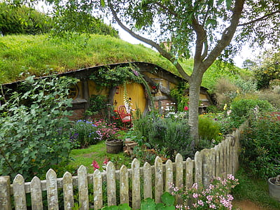 brown wooden house with gray wooden fence near green hill at daytime thumbnail