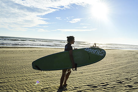 woman carrying gray surfboard on seashore thumbnail