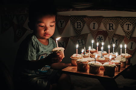 boy holding cupcake with lightning candle beside happy birthday buntings thumbnail