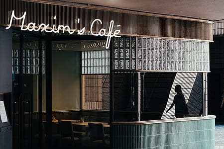 person walking beside Maxim's Cafe store thumbnail