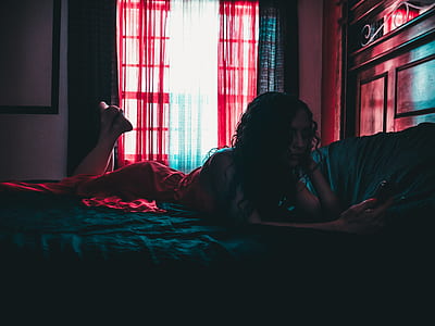 woman lying on bed holding smartphone thumbnail