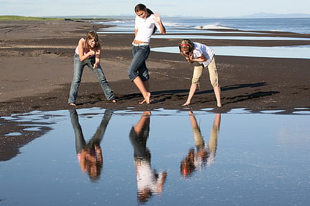 three women watching their reflection on calm body of water during daytime thumbnail